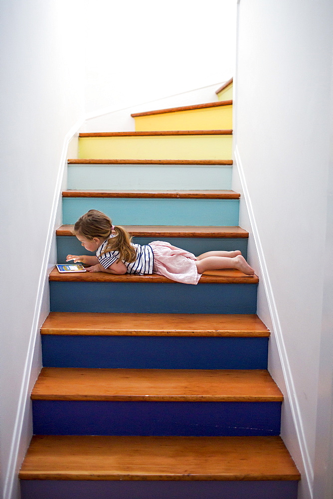 Caucasian girl using digital tablet on multicolor staircase