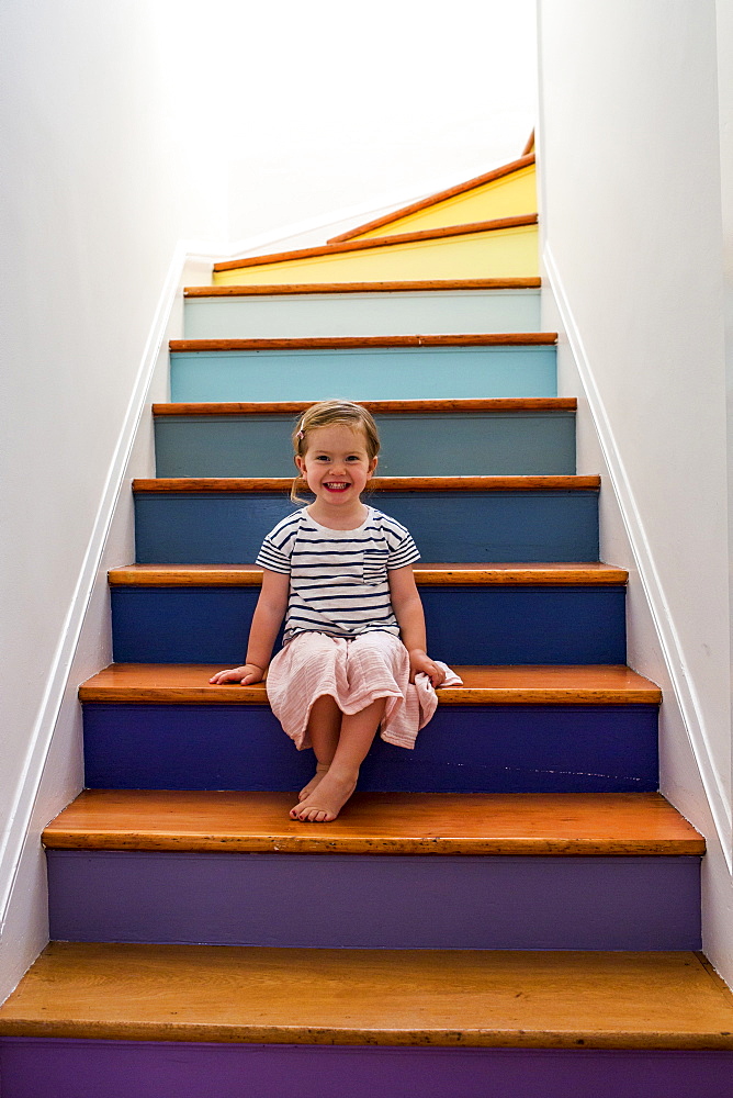 Portrait of smiling Caucasian girl sitting on multicolor staircase