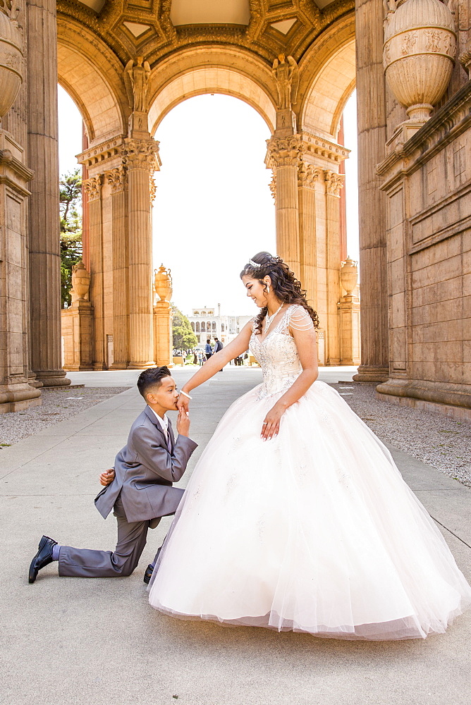 Hispanic boy wearing suit kissing hand of girl wearing gown