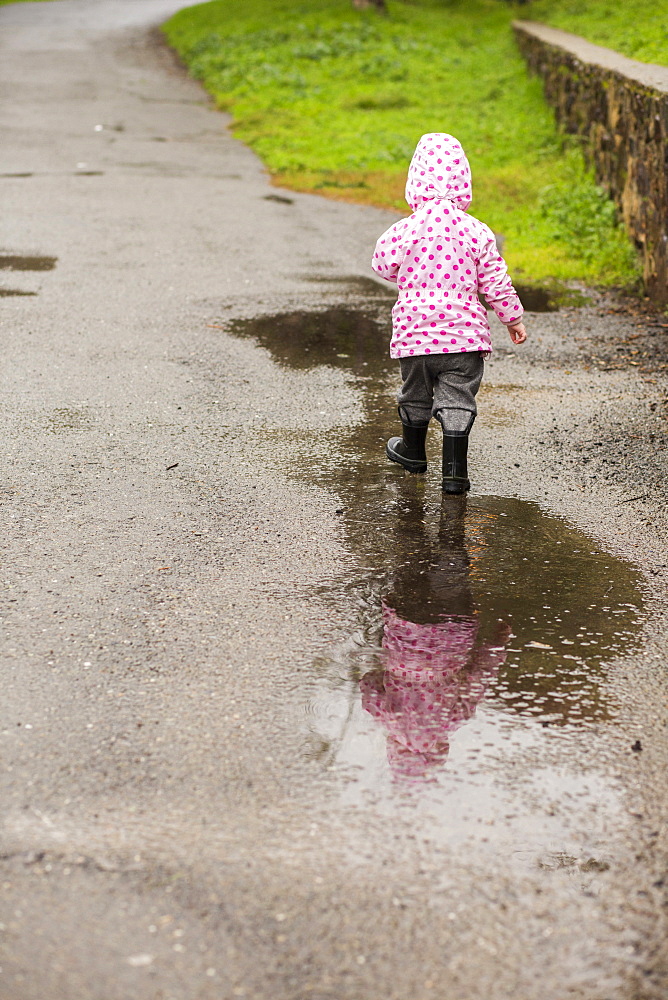 Caucasian girl wearing boots walking in puddle