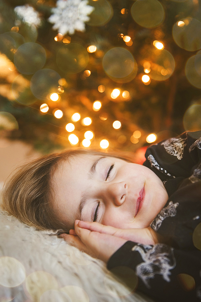 Caucasian girl sleeping near Christmas tree