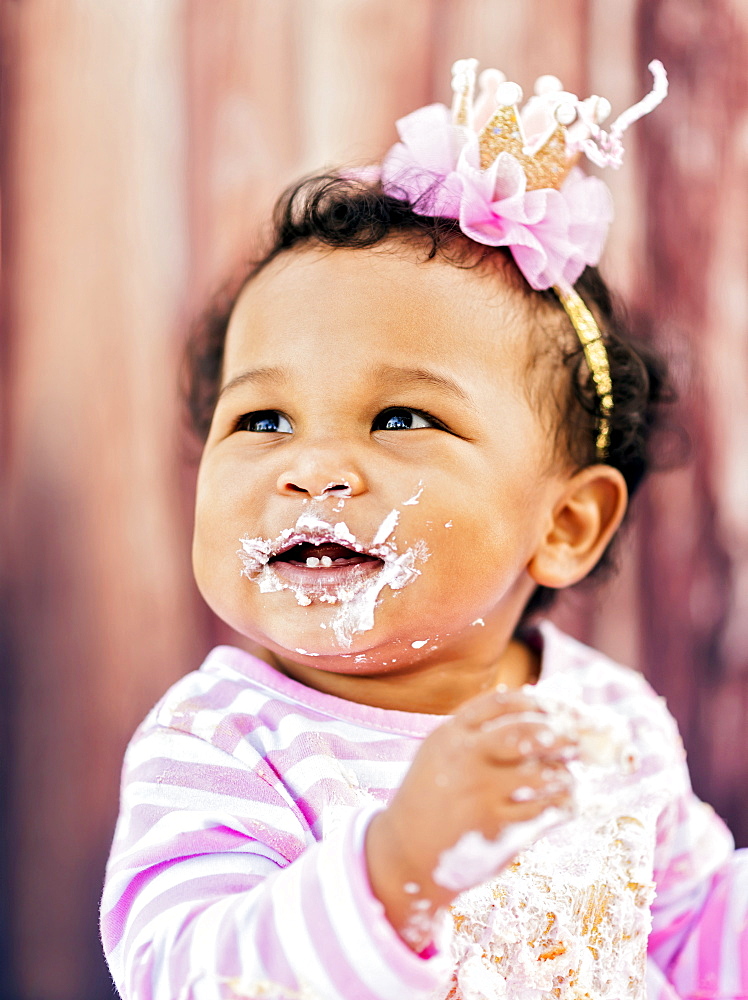 Messy Mixed Race baby eating birthday cake