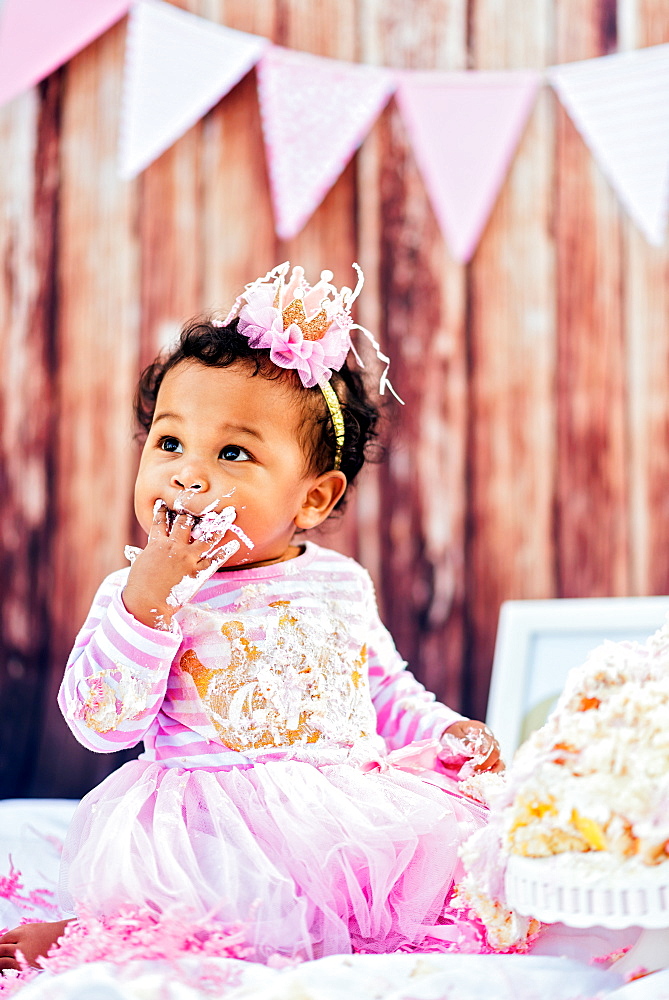 Mixed Race baby eating birthday cake