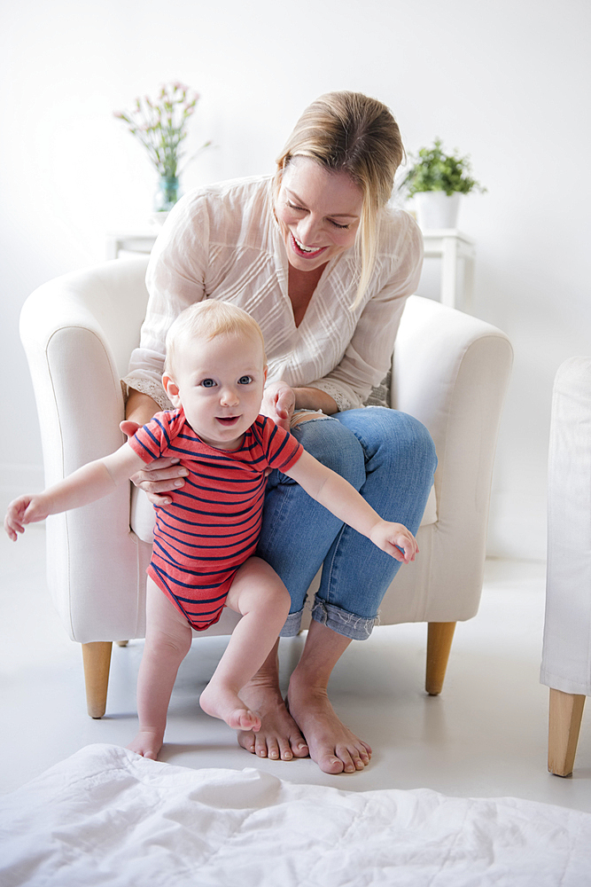 Caucasian mother helping walking baby son