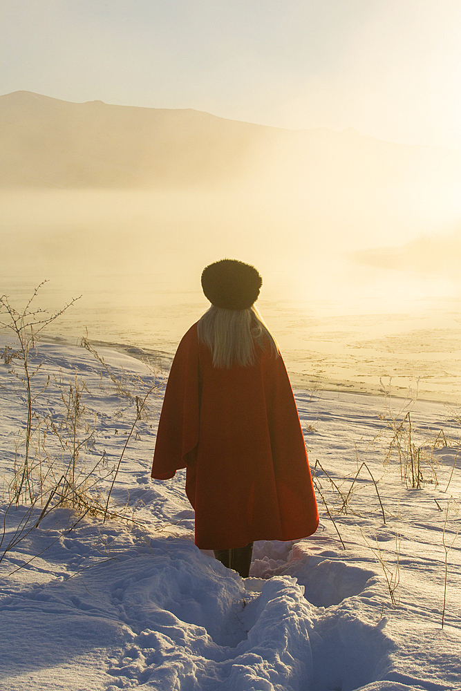 Caucasian woman standing in winter landscape at sunset