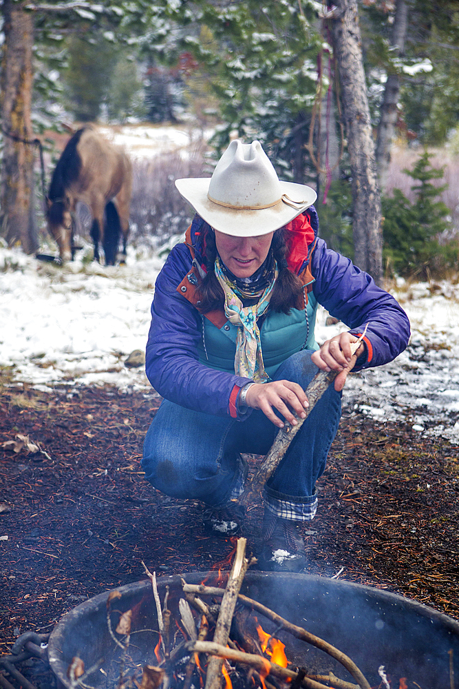 Caucasian woman putting wood in campfire