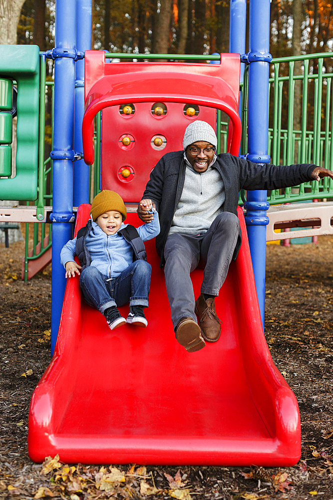 Father and son on playground slide in park