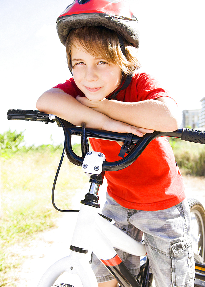 Caucasian boy leaning on bicycle handlebar