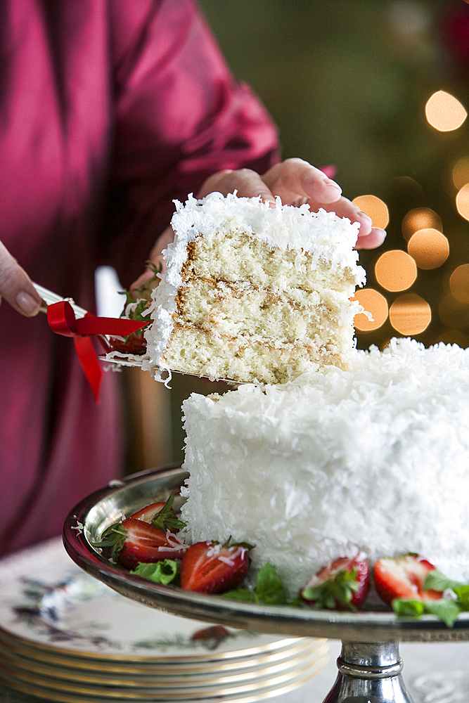 Hands serving slice of coconut cake