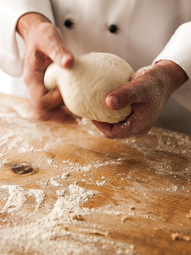 Hands of baker kneading dough