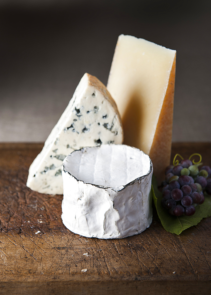 Artisanal cheese and grapes on wooden table