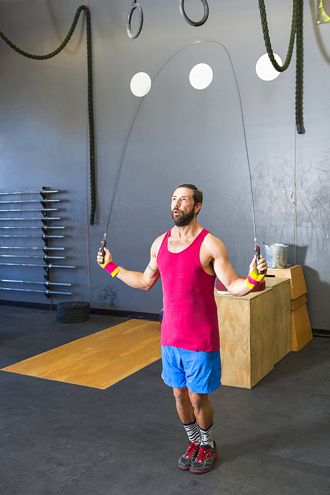 Mixed Race man jumping rope in gymnasium