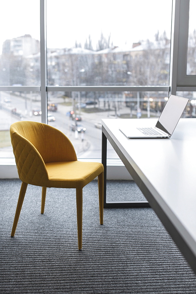 Laptop and chair near window in city