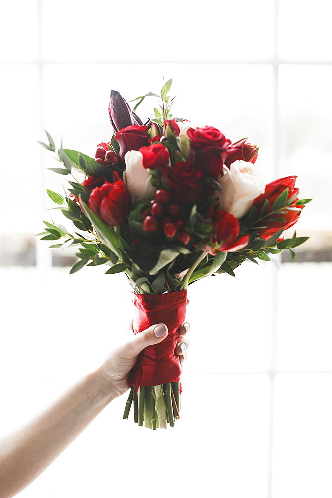 Hand of Caucasian woman holding bouquet of flowers