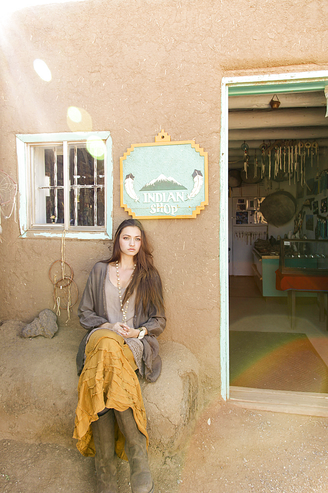 Hispanic teenage girl sitting near doorway to shop