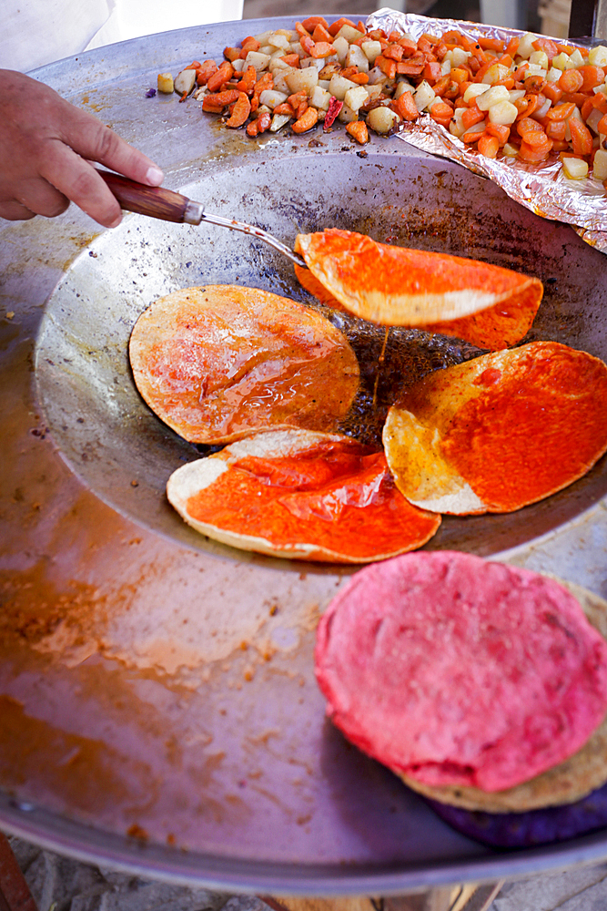 Hand flipping fresh tortillas in pan