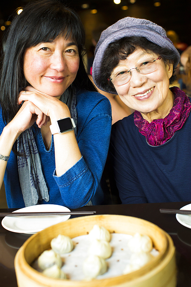 Older Japanese mother and daughter smiling in restaurant