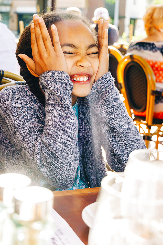 Smiling Mixed Race girl making a face at restaurant table