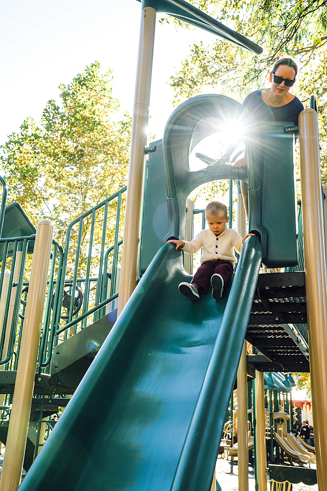 Mother watching son on playground slide