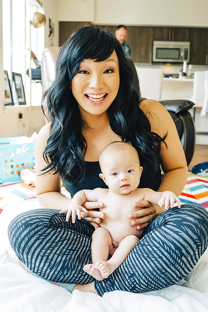 Portrait of mother sitting with baby daughter in lap