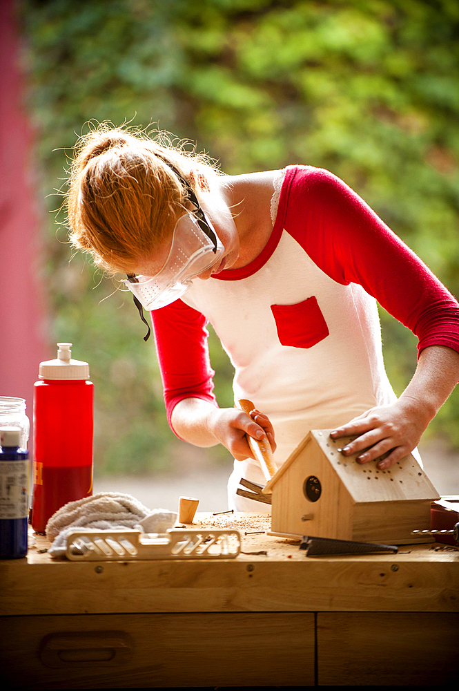 Girl hammering nails into birdhouse