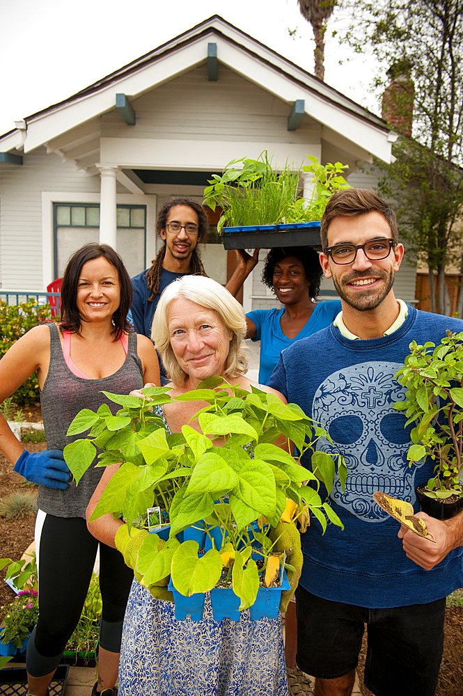 Portrait of neighbors holding plants near house