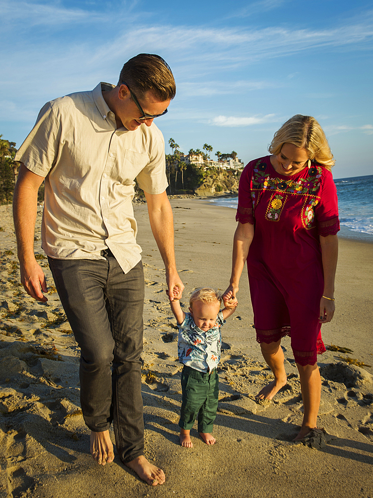 Caucasian mother and father walking baby son on beach