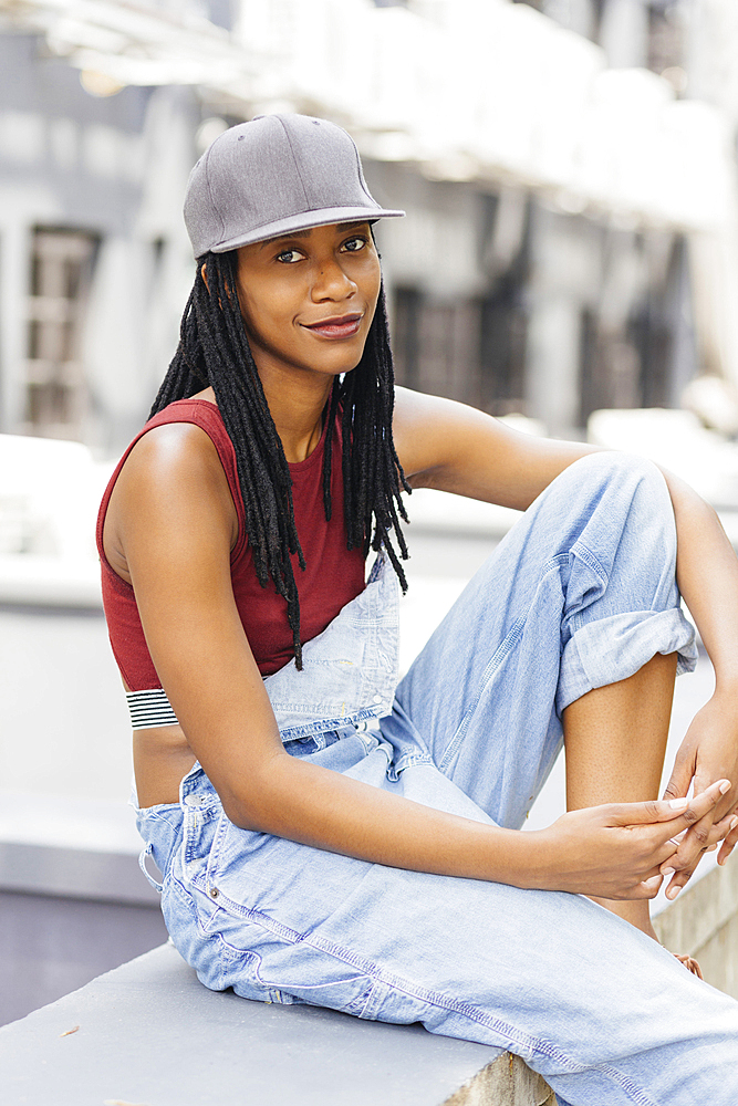 Smiling Mixed Race woman sitting on wall