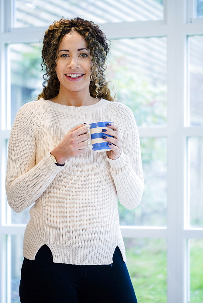 Woman standing near window holding coffee cup