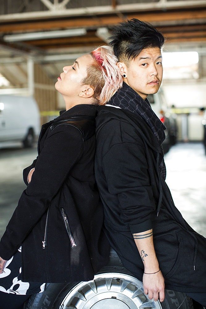 Androgynous Asian man and woman sitting on wheel