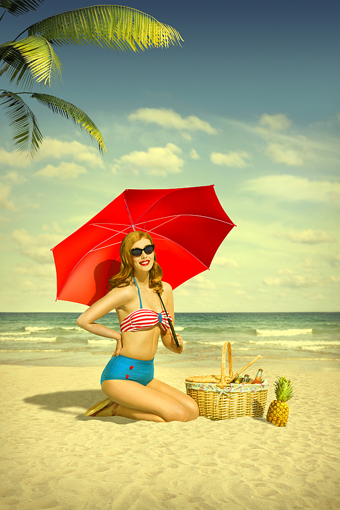 Caucasian woman holding red umbrella at beach