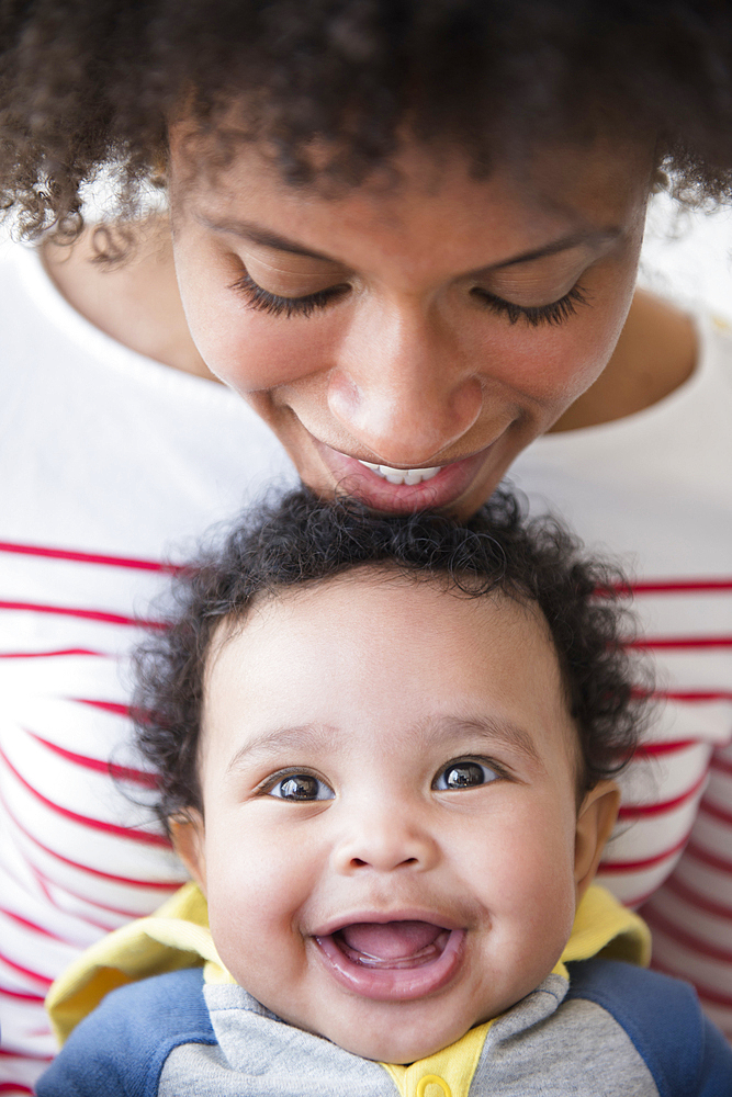 Smiling mother leaning chin on head of baby son