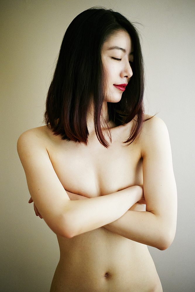 Naked Asian woman with arms crossed covering breasts