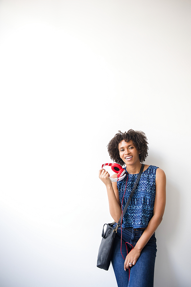 Black woman carrying purse holding headphones