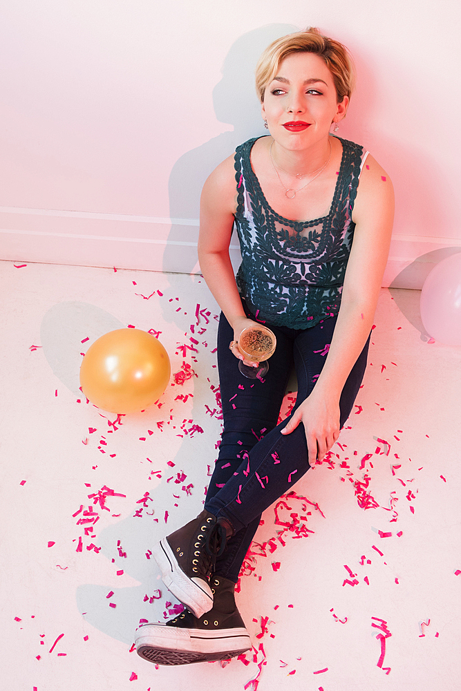 Caucasian woman sitting on floor at party covered in confetti