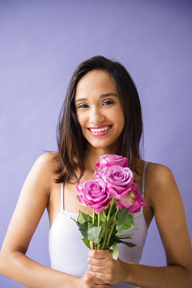 Smiling Mixed Race woman holding bouquet of roses