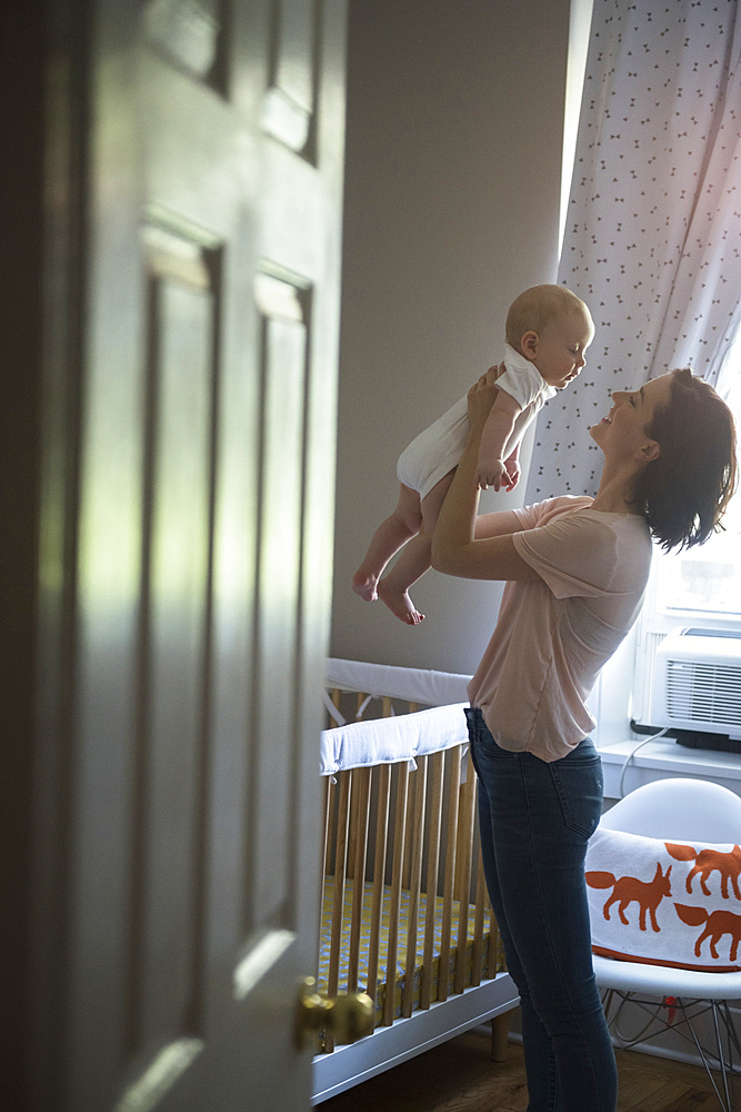 Caucasian mother holding baby son face to face in bedroom