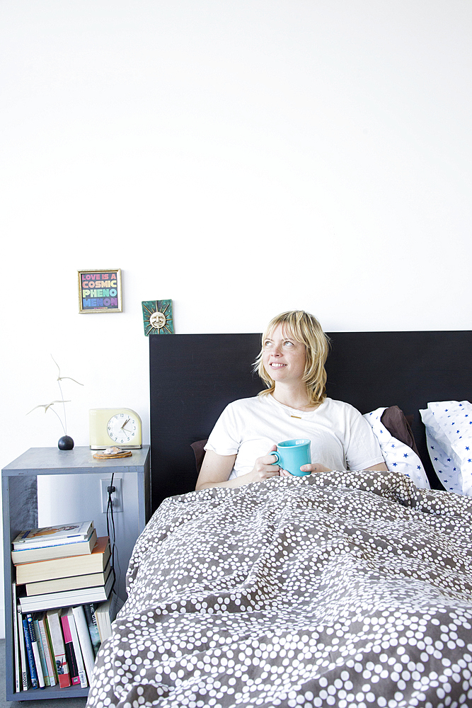 Caucasian woman drinking coffee in bed