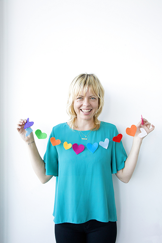 Caucasian woman holding string of paper hearts