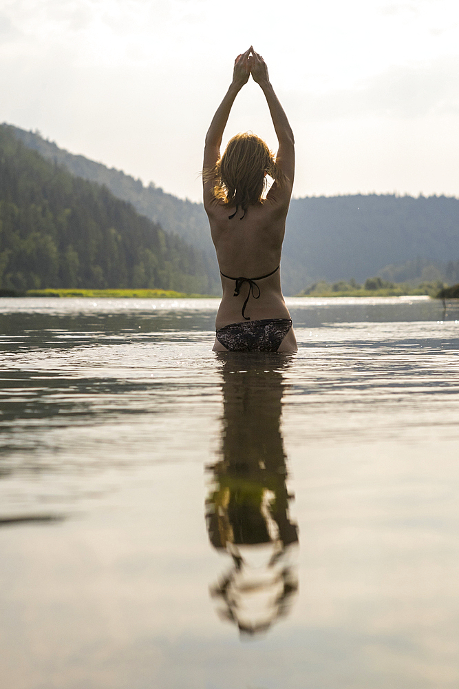 Caucasian woman standing in lake wearing bikini