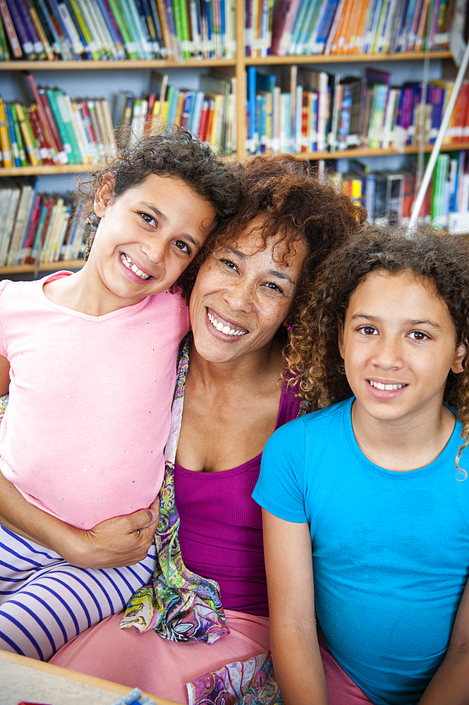 Smiling mother posing with daughters in library