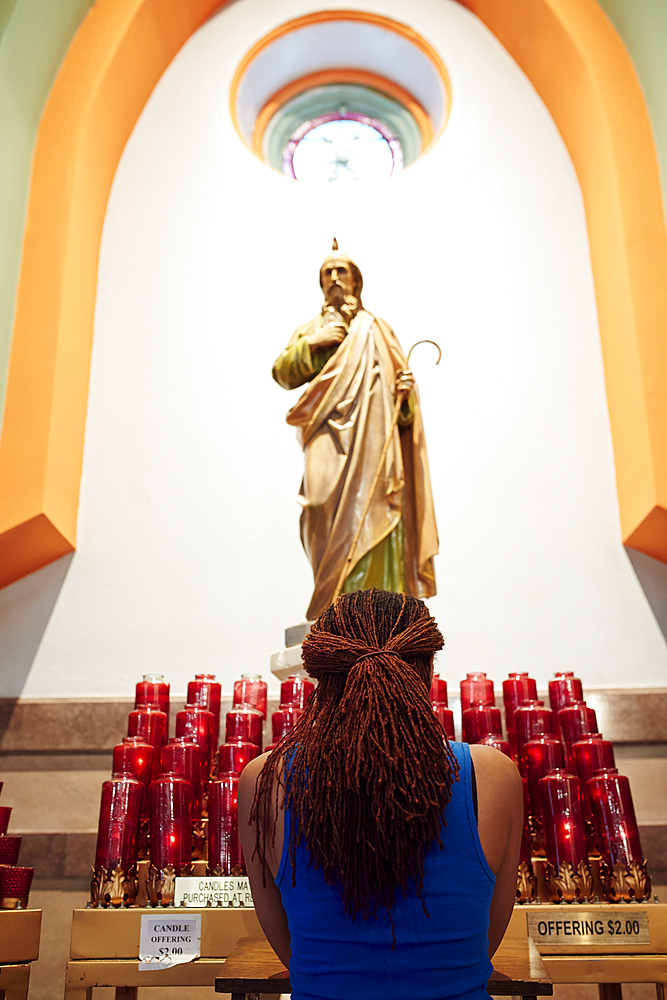 Kneeling woman praying to statue in church