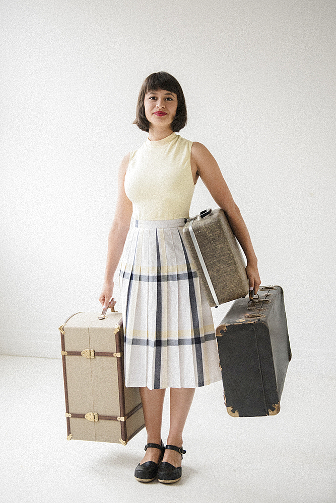 Portrait of smiling Hispanic woman holding suitcases