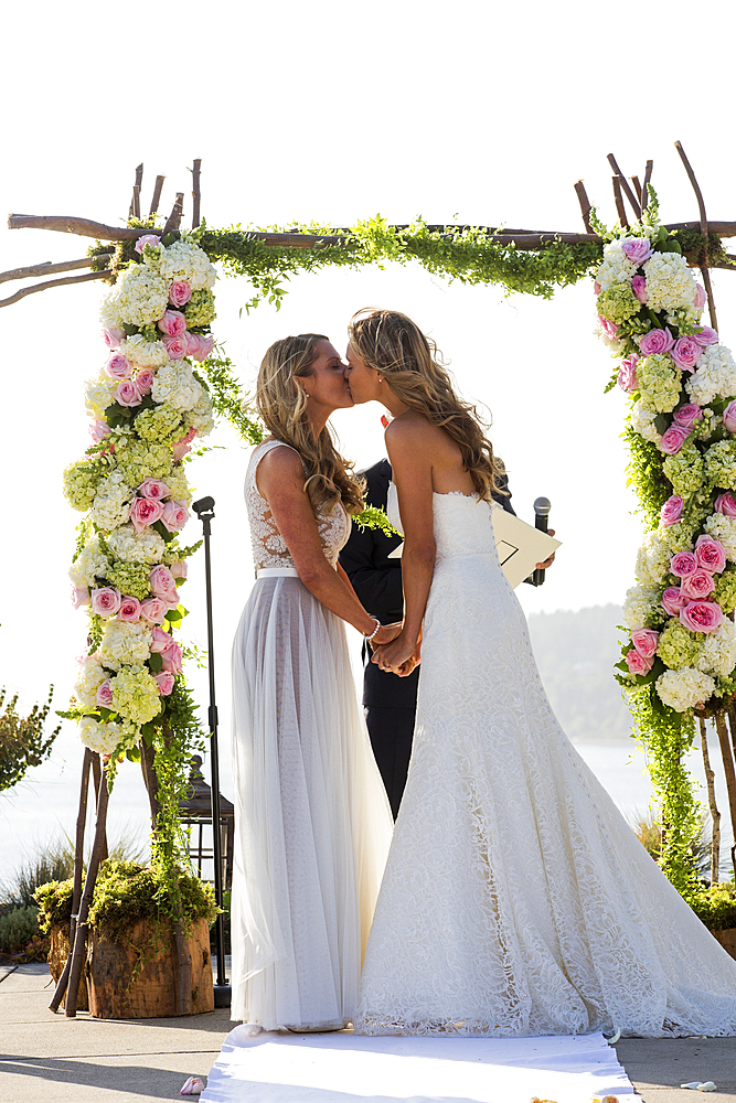 Caucasian brides kissing at wedding ceremony