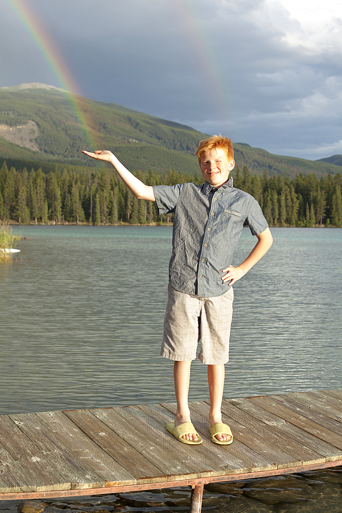 Caucasian boy posing on dock catching rainbow