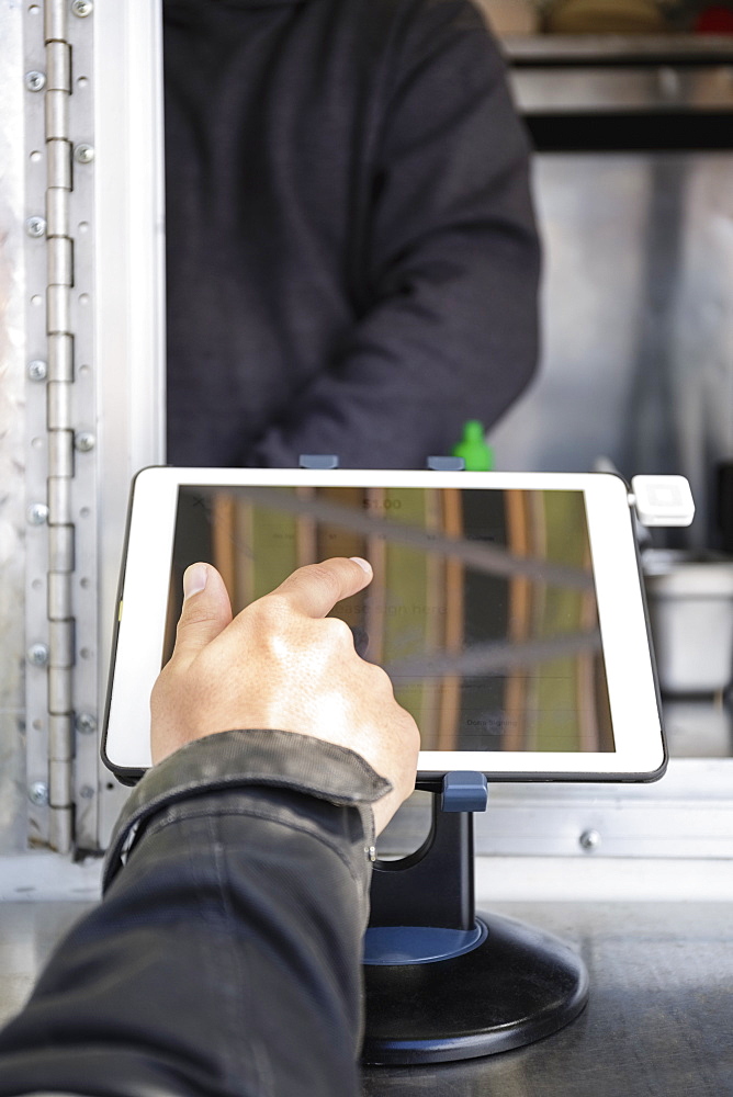 Man paying at food cart using digital tablet