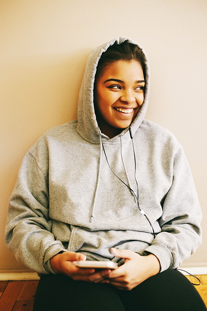 Mixed Race woman sitting on floor listening to cell phone