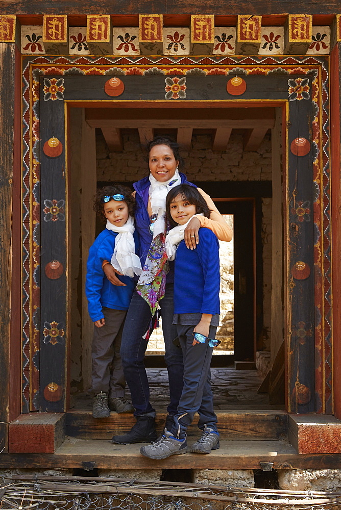 Mixed Race mother hugging sons in doorway