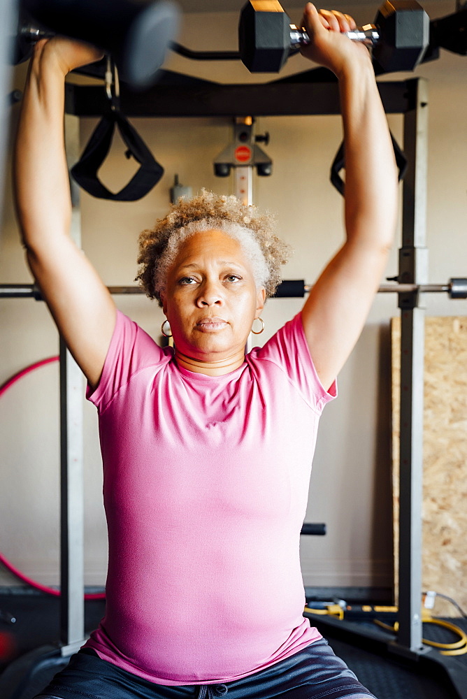 Black woman lifting weights in garage