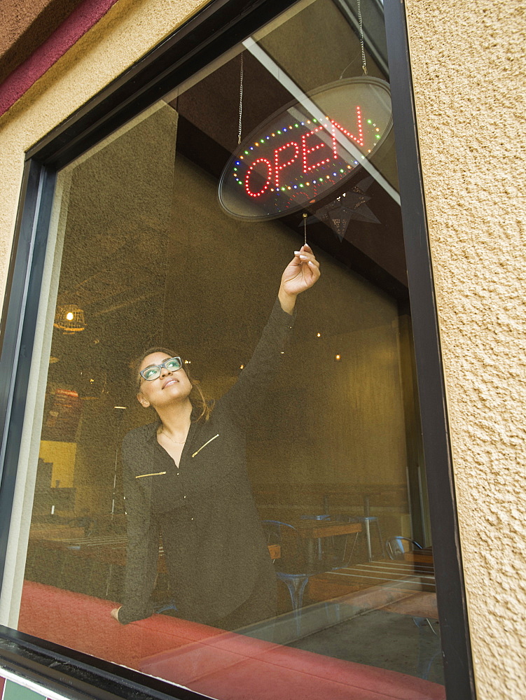 Hispanic business owner using open sign